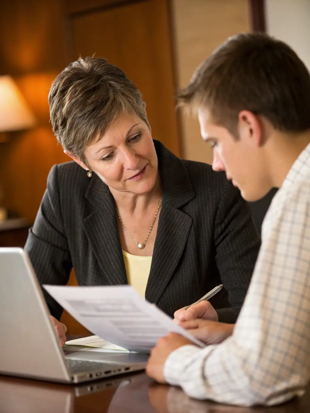 A professional portrait of a financial advisor explaining the benefits of cash value life insurance to a young family in a modern office setting.